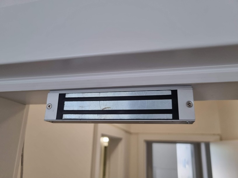 Detail instalovaného dveřního elektromagnetu s přídržnou silou 280 kg na zárubni dveří s magnetickou střelkou.