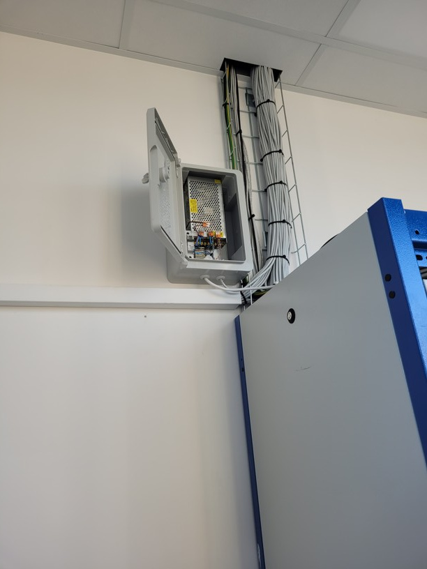 Čistě usazený a zapojený napájecí rozvaděč vedle datového racku ve firemních prostorech.
