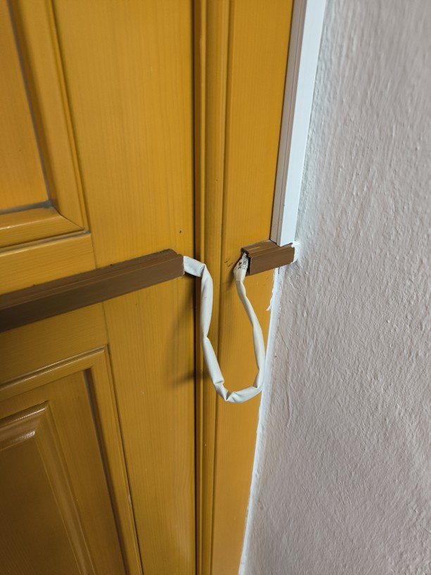 Amatérská instalace předchozí firmy – kabel vedený povrchově v liště a ohyb chráněný pouze smršťovací bužírkou místo průchodky.