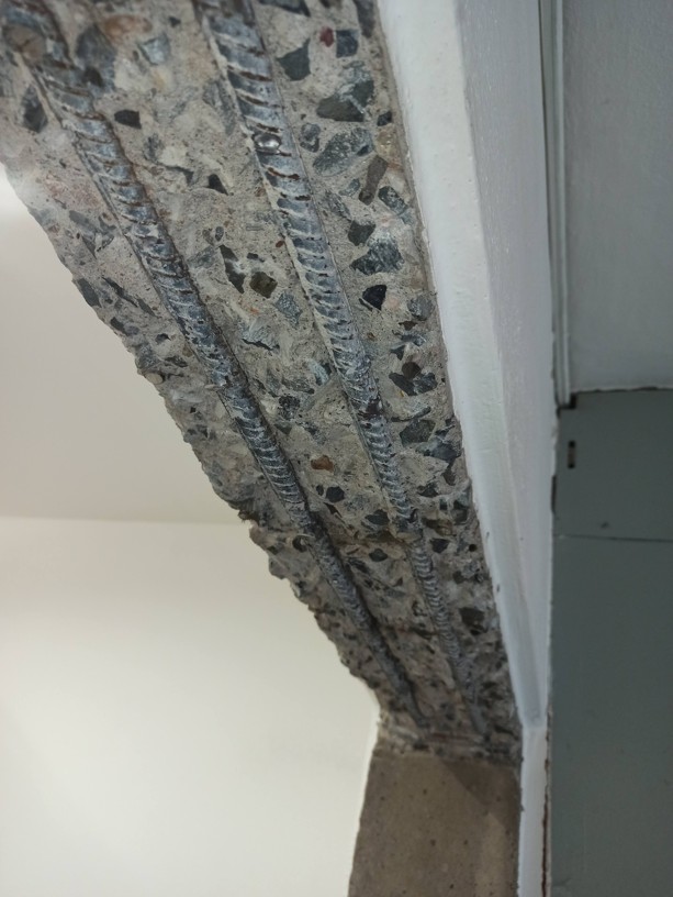 Odkrytý betonový panel s ocelovými roxory po vybourání staré kovové zárubně při přípravě stavebního otvoru.