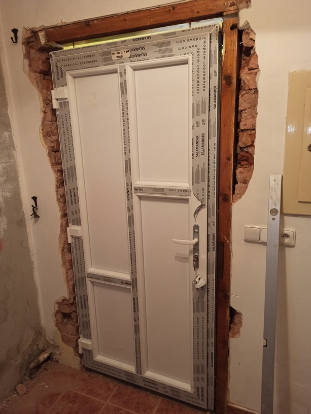 Ukotvení a vypěnění izolační pěnou u nově montovaných plastových dveří pro rodinný dům.