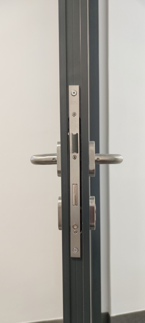 Čistá montáž zadlabacího panikového zámku do úzkého hliníkového profilu dveří na únikové trase.