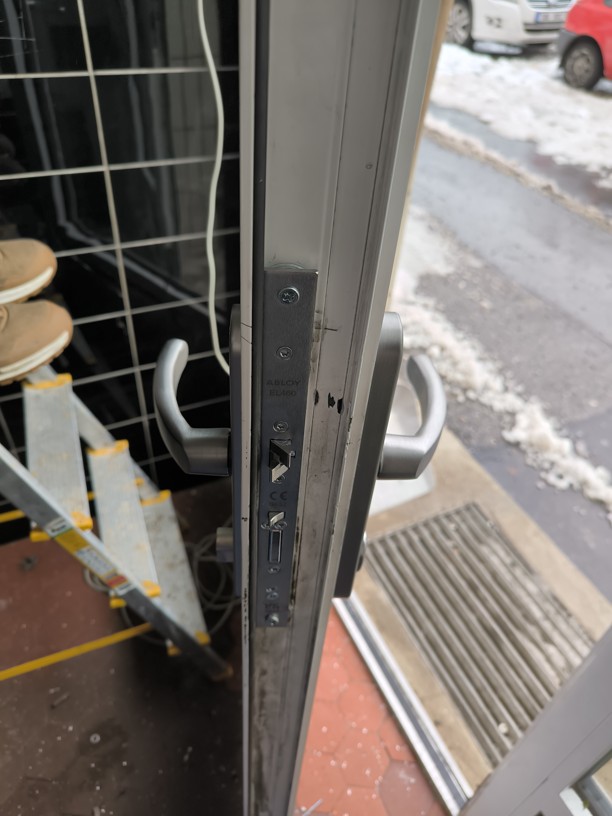 Odborně instalovaný elektromechanický samozamykací zámek ABLOY EL460 v hraně hliníkových dveří.