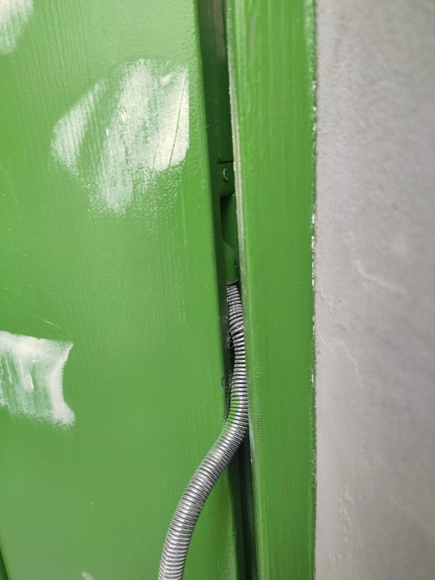 Zdeformovaná ochranná hadice kabelového přechodu, která se při zavírání skřípe o hranu zárubně