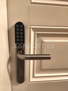 Detail montáže moderního elektronického kování na interiérových dveřích. Chytrý zámek umožňuje bezklíčové otevírání pomocí PIN kódu na klávesnici, přiložením RFID čipu nebo přes mobilní aplikaci. Ideální řešení přístupového systému pro krátkodobé pronájmy