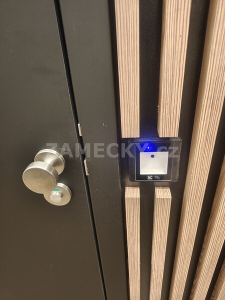 Detail instalace čtečky QR kódů pro automatické otevírání dveří na toalety (WC). Přístupový systém s elegantním zapuštěním do dřevěného obkladu umožňuje kontrolovaný vstup po naskenování platného QR kódu z účtenky nebo mobilního telefonu. Skvělé řešení pr